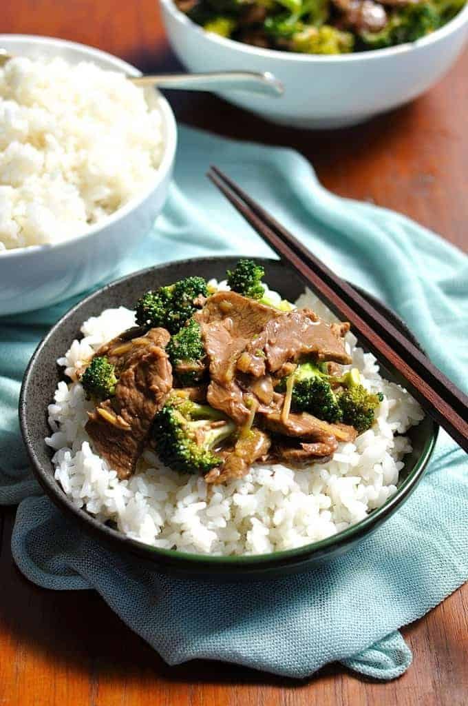 Slow Cooker Beef and Broccoli in a dark bowl with blue cloth