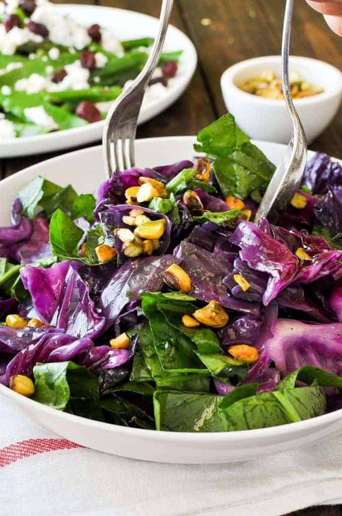 Warm Red Cabbage Salad with Garlic Herb Butter being tossed in a salad bowl.