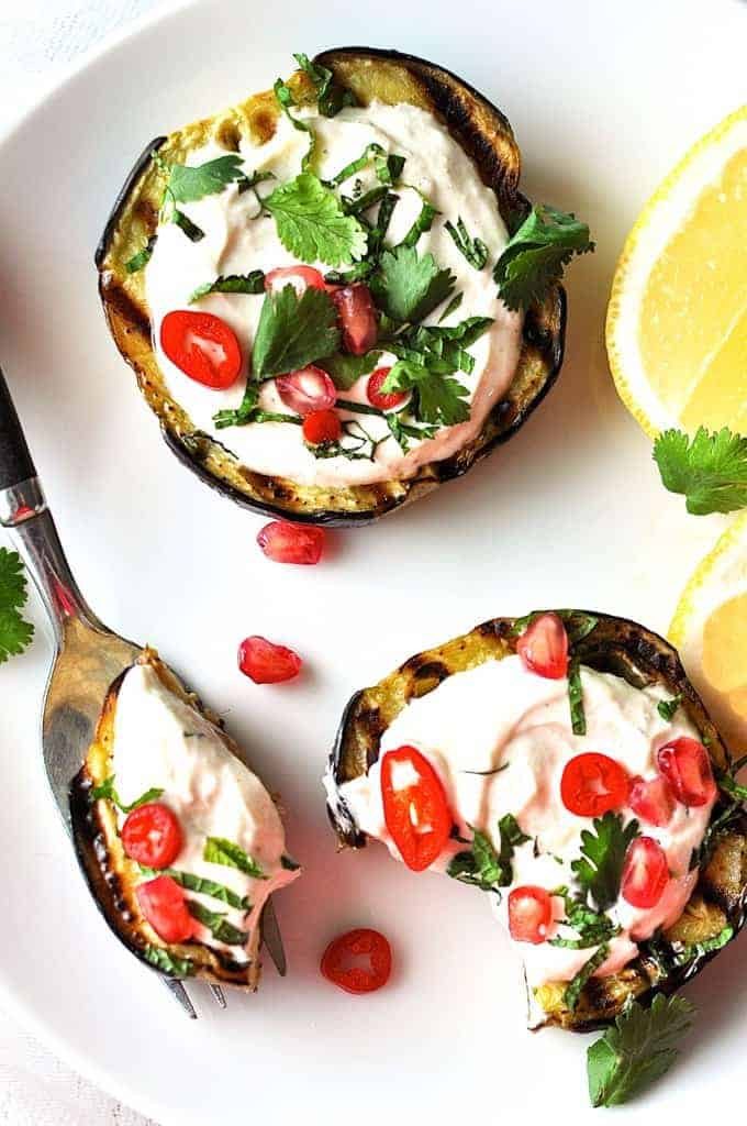 Grilled Eggplant discs topped with yoghurt sauce, pomegranate and coriander