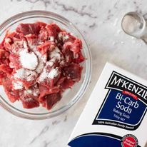 Slices of beef in a bowl being tenderised the Chinese Restaurant way using backing soda