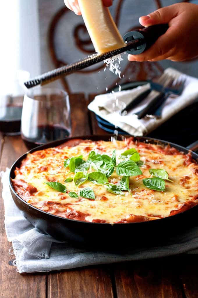Grating parmesan over Creamy Tomato Pasta Bake With Chicken