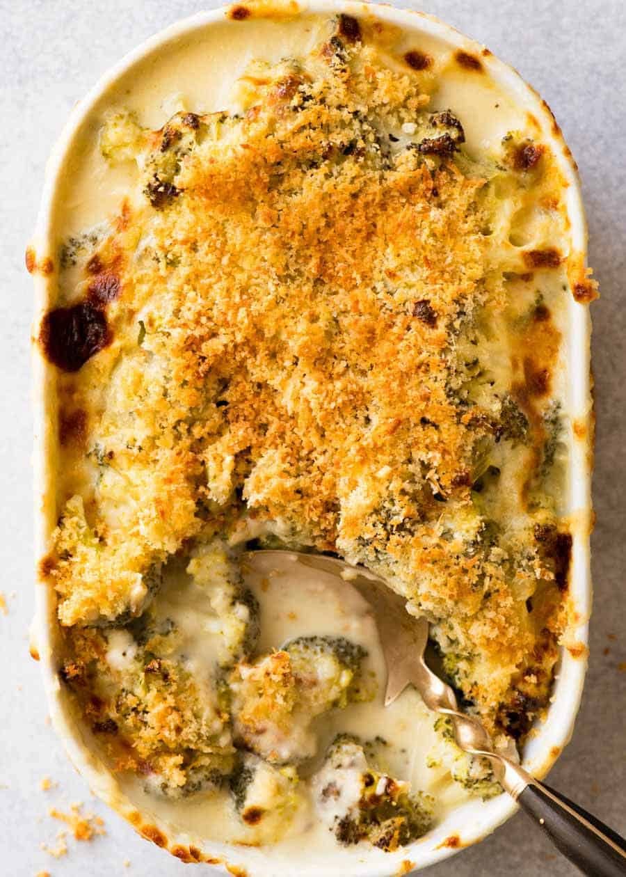 Overhead photo of creamy Broccoli Casserole topped with a golden crunchy topping in a white casserole dish, fresh out of the oven ready to be served.