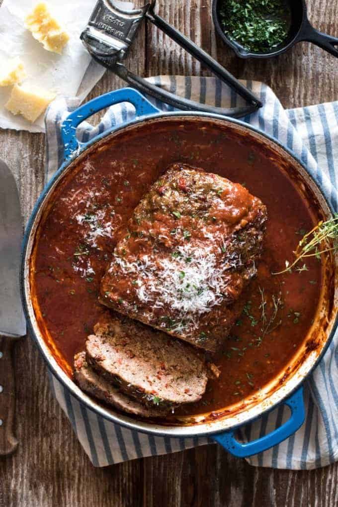 Italian Meatloaf with tomato marinara sauce in a round blue casserole pan sitting on a tea towel.