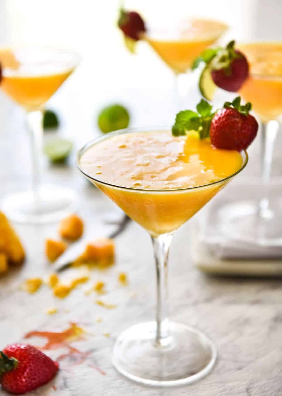 Frozen Mango Daquiris in cocktail glasses, garnished with strawberries.