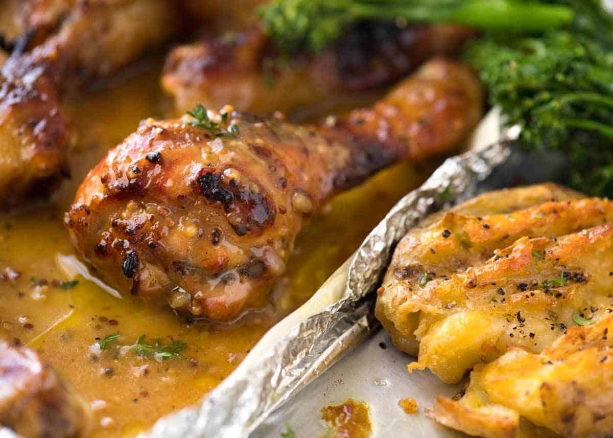 Close up of sticky Honey Mustard Chicken Drumsticks and crispy smashed potatoes, fresh out of the oven.