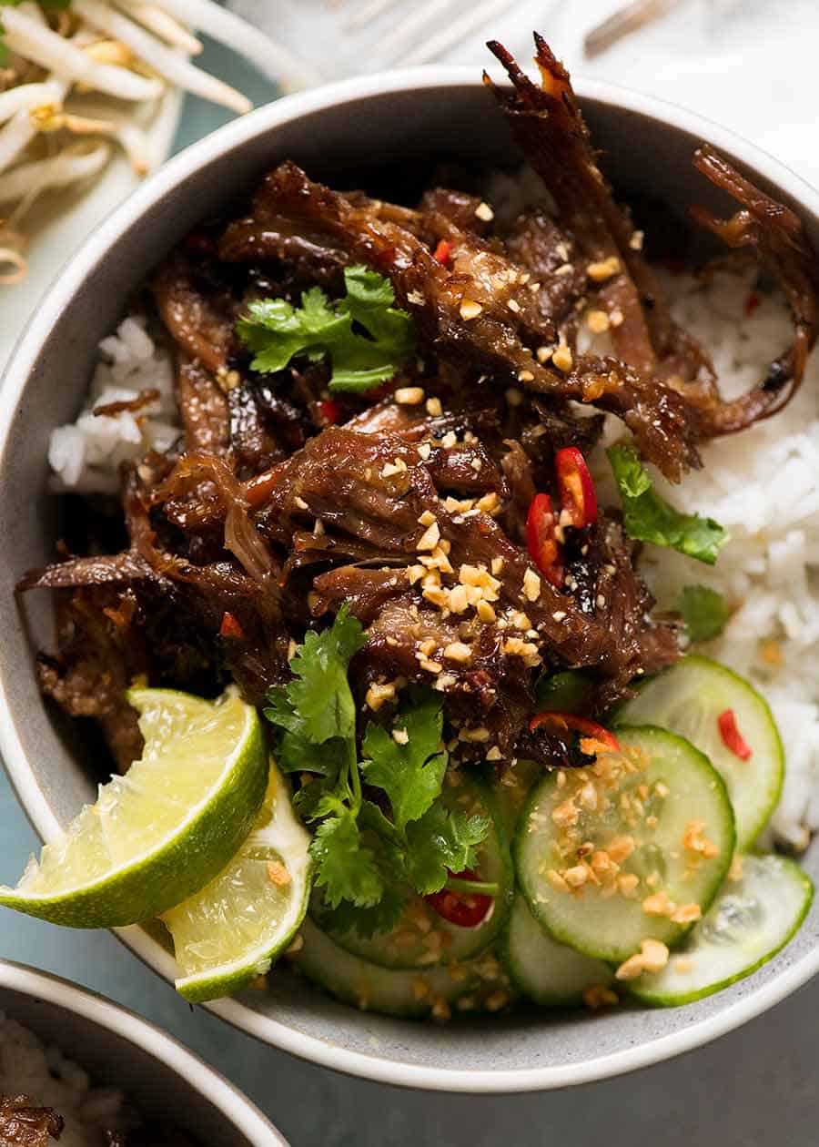Overhead photo of Caramelised Vietnamese Shredded Beef served over rice with lime wedges, cucumber, chilli and peanuts