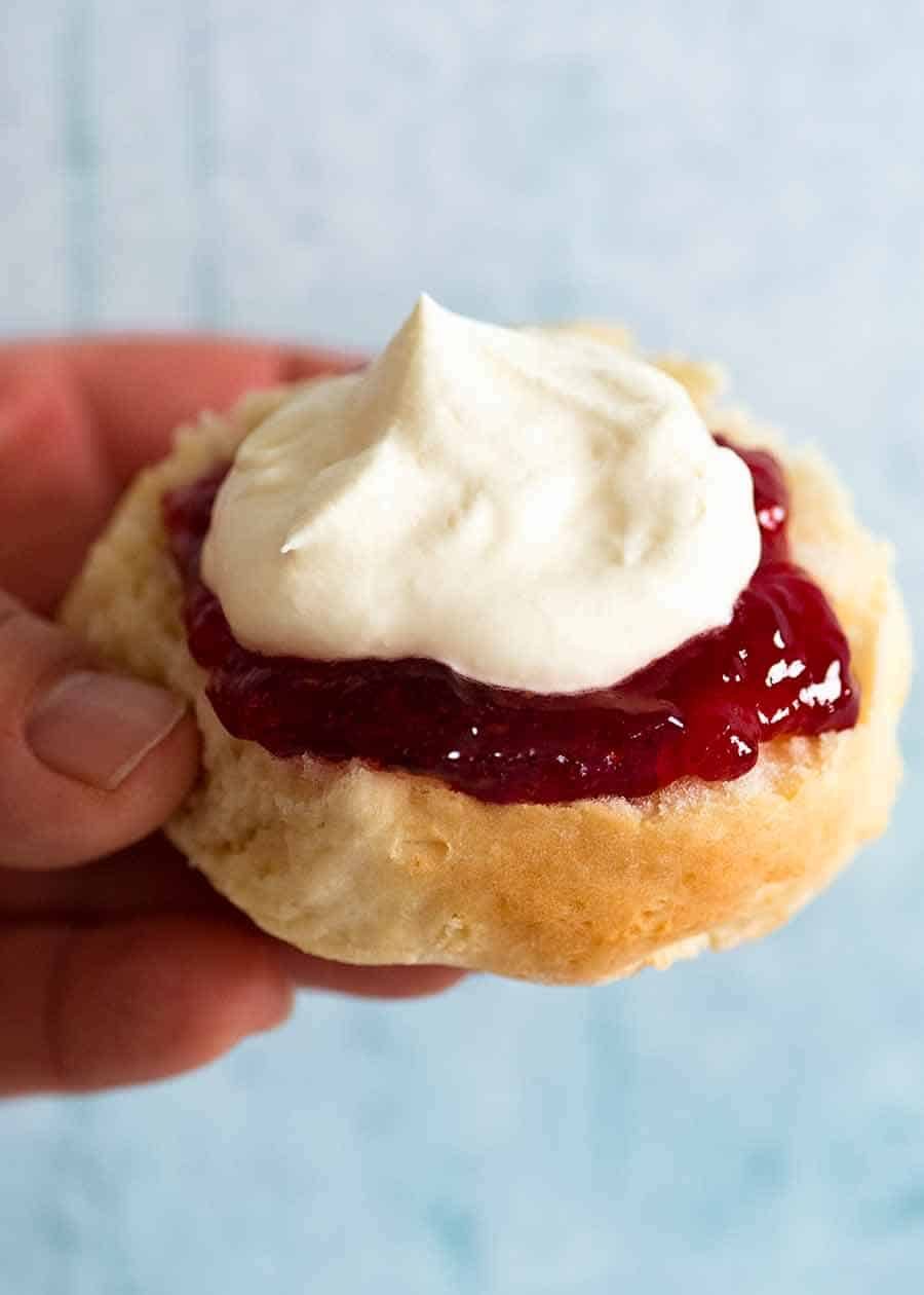 Hand holding Lemonade Scones with jam and cream