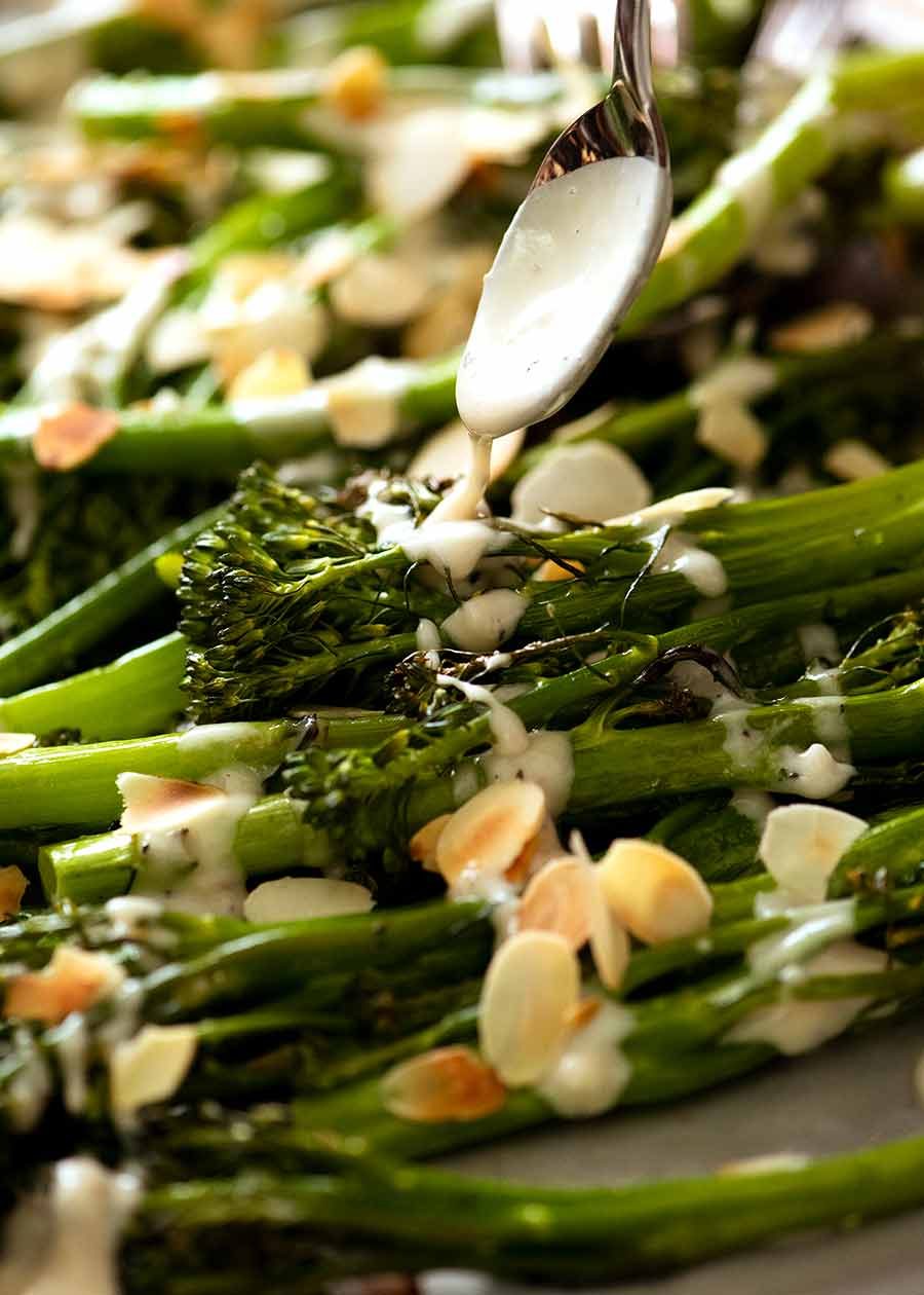 Drizzling tahini sauce over roasted broccolini