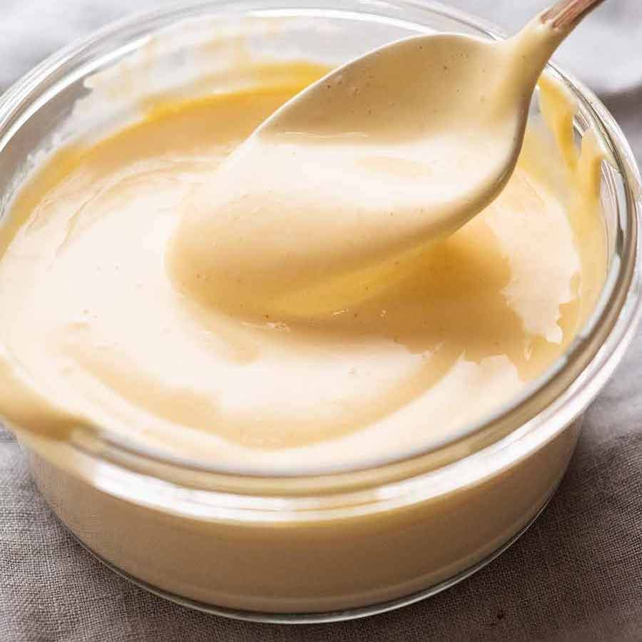 Hollandaise Sauce in a bowl being scooped by spoon