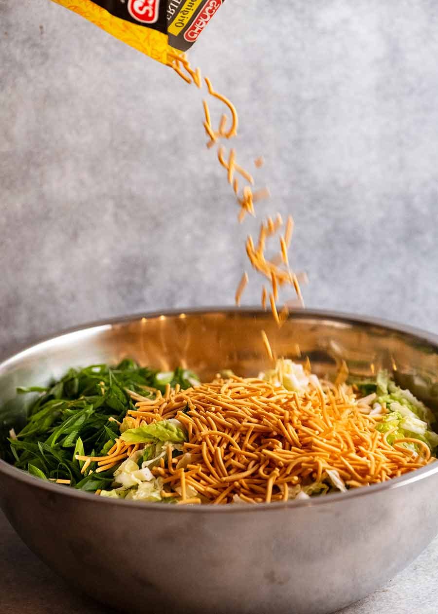 Scattering crispy noodles over crispy noodle salad
