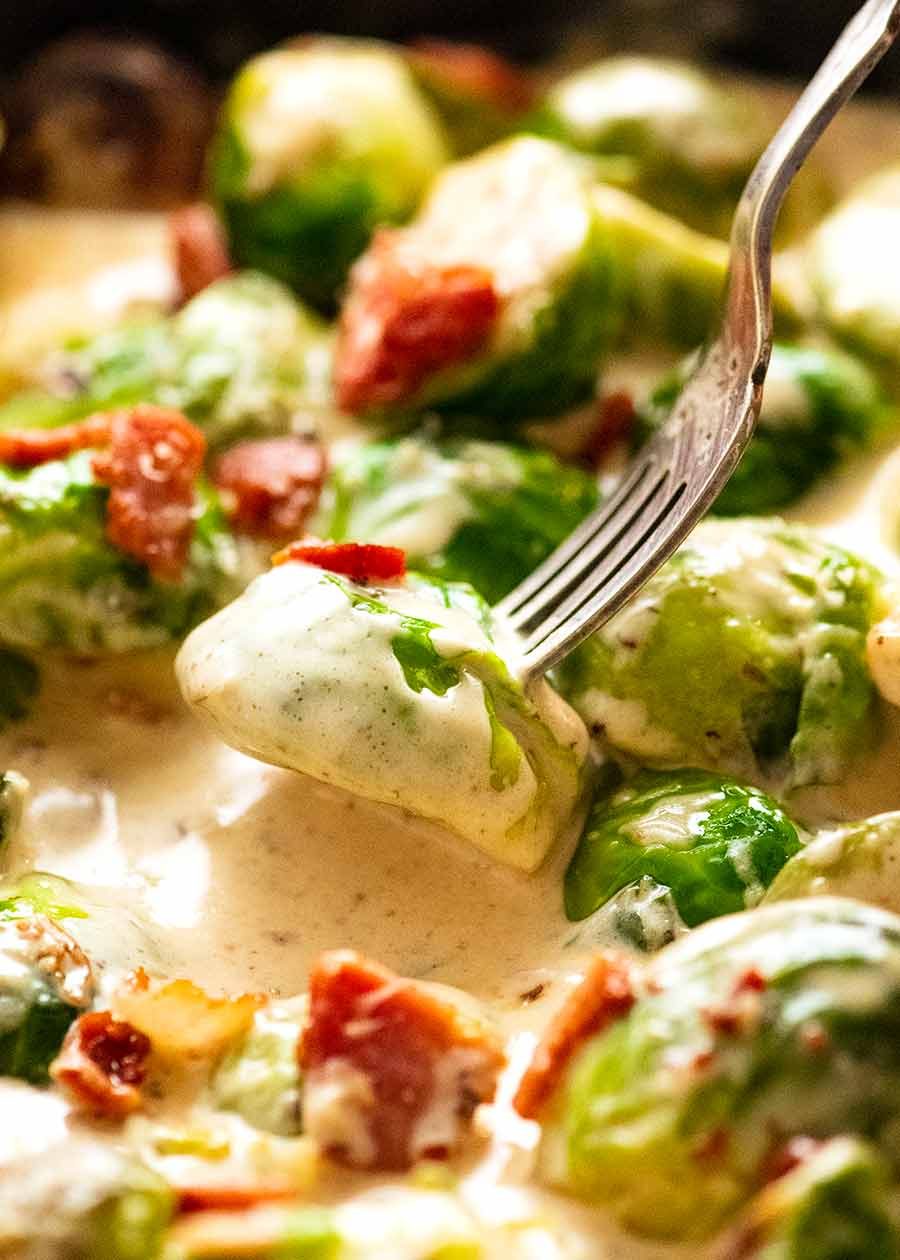 Fork picking up sautéed Brussels sprouts in a creamy sauce