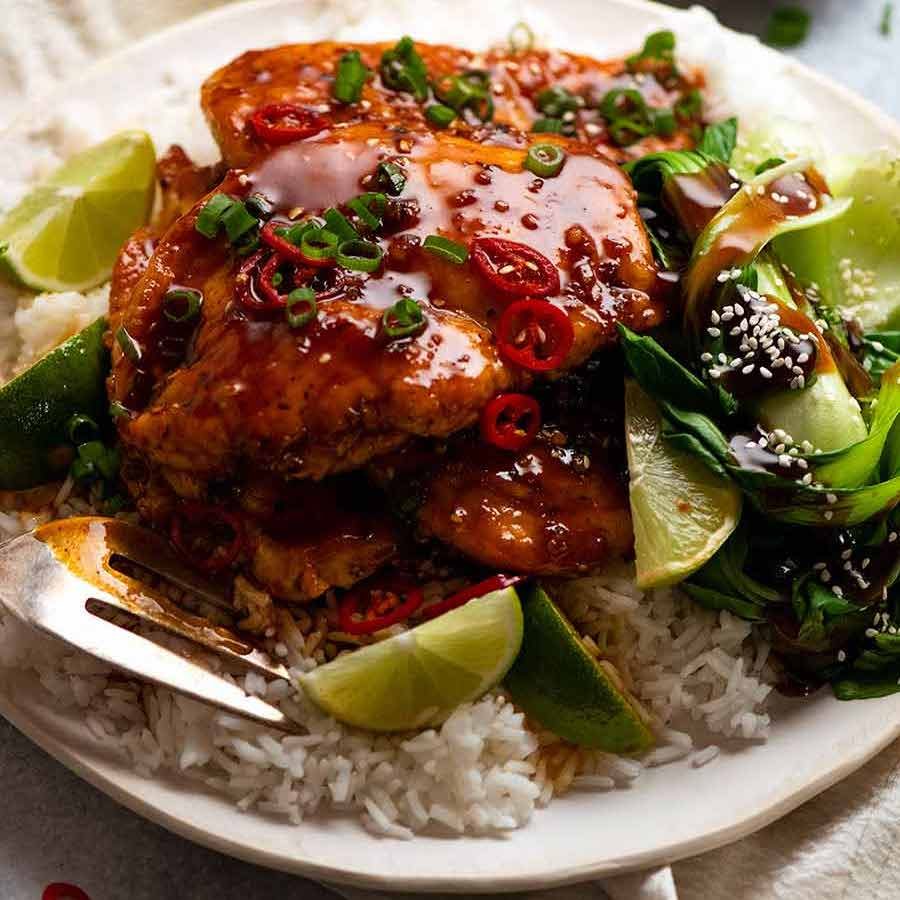 Pile of Asian Chilli Chicken served over rice with steamed asian greens on the side